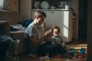 Батько сидить на підлозі в захаращеній іграшками квартирі, з розпачем дивлячись у телефон, поки дружина поїхала в готель, щоб він зрозумів, як це — бути мамою в декреті 24/7.