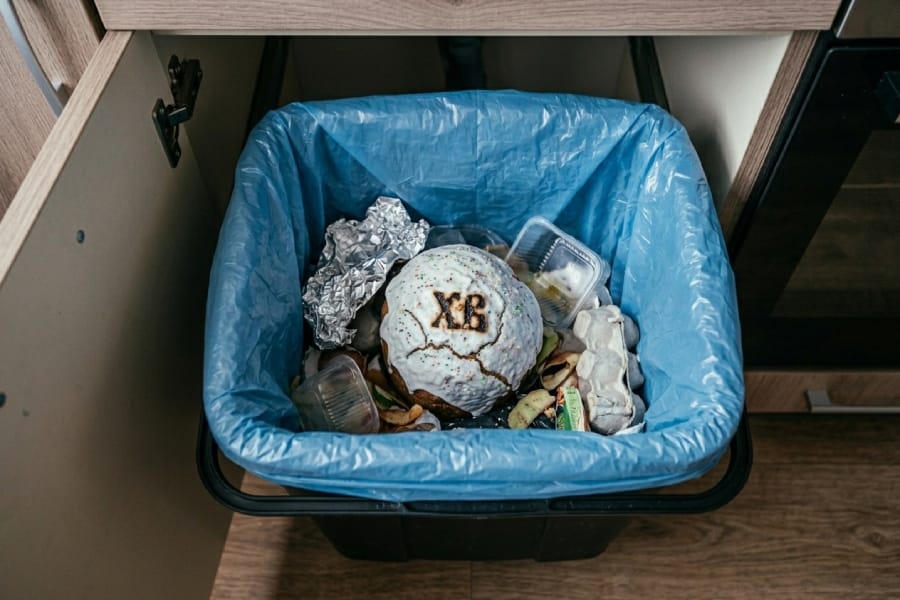 Великодня паска з символами ХВ лежить у блакитному сміттєвому пакеті всередині кухонної тумби.